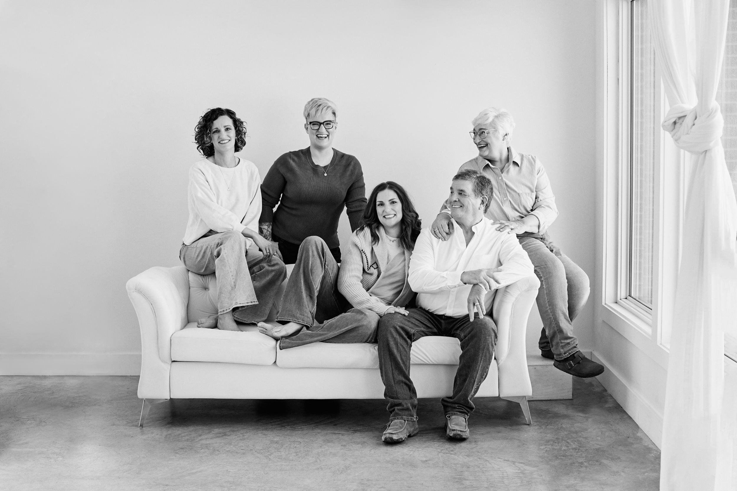 Black and white photo series of people relaxing and posing on a white couch.