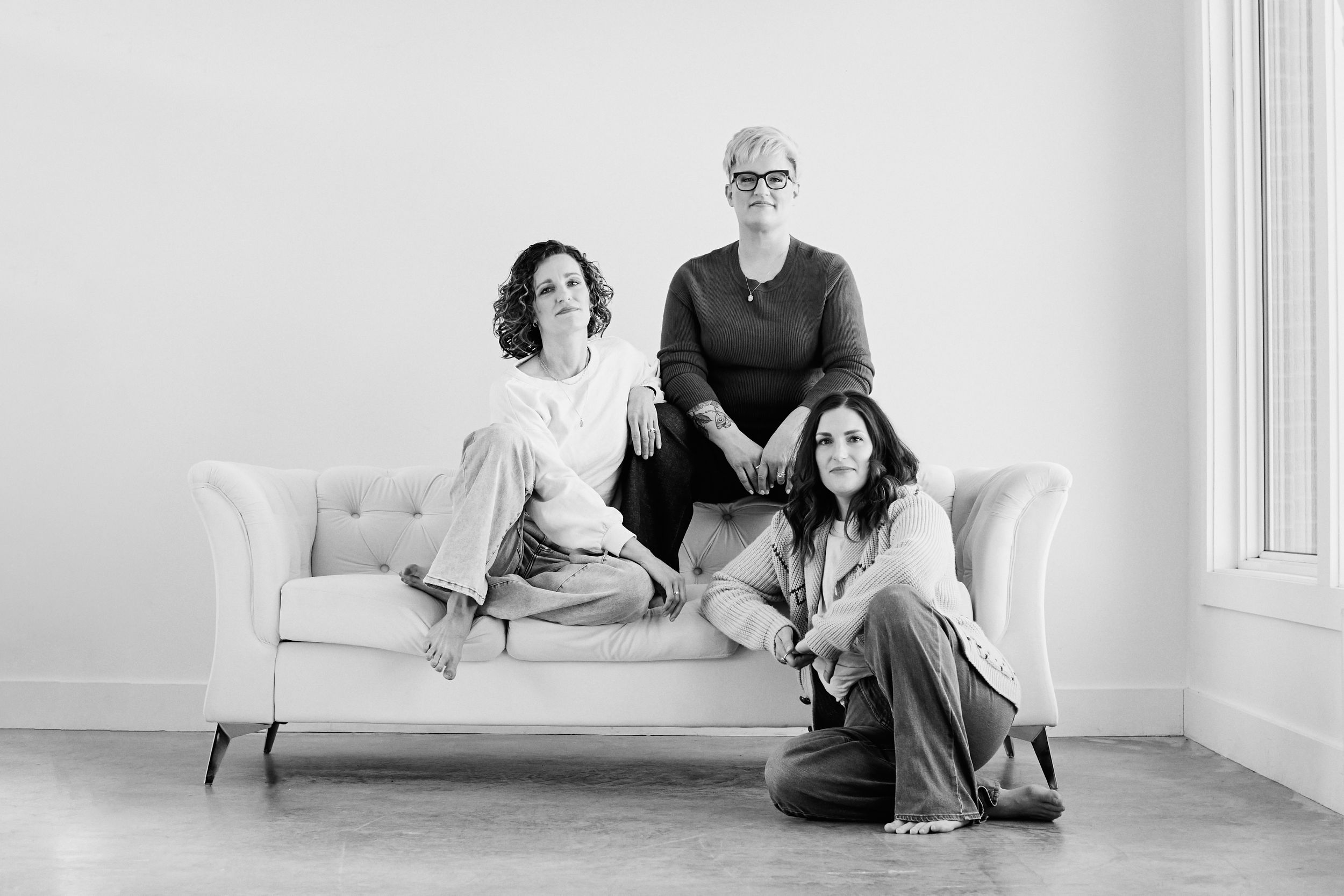 Black and white portraits of people lounging and interacting on a white couch in different poses.