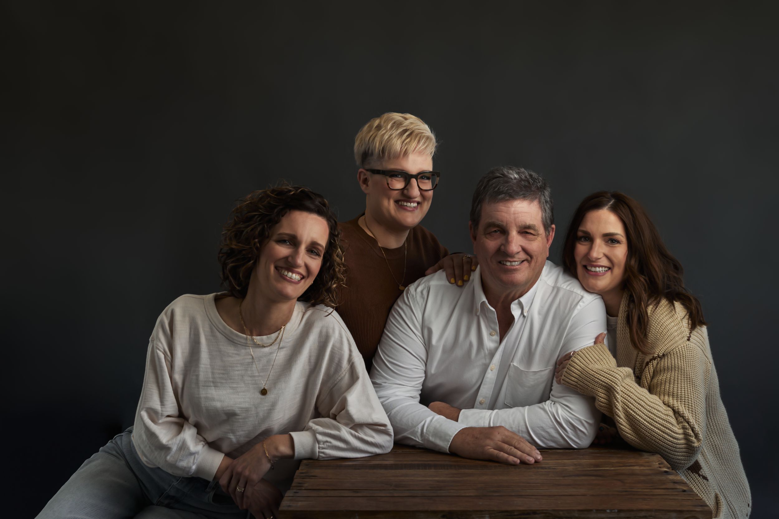 Dark moody portrait series showing a group in casual poses against black background.