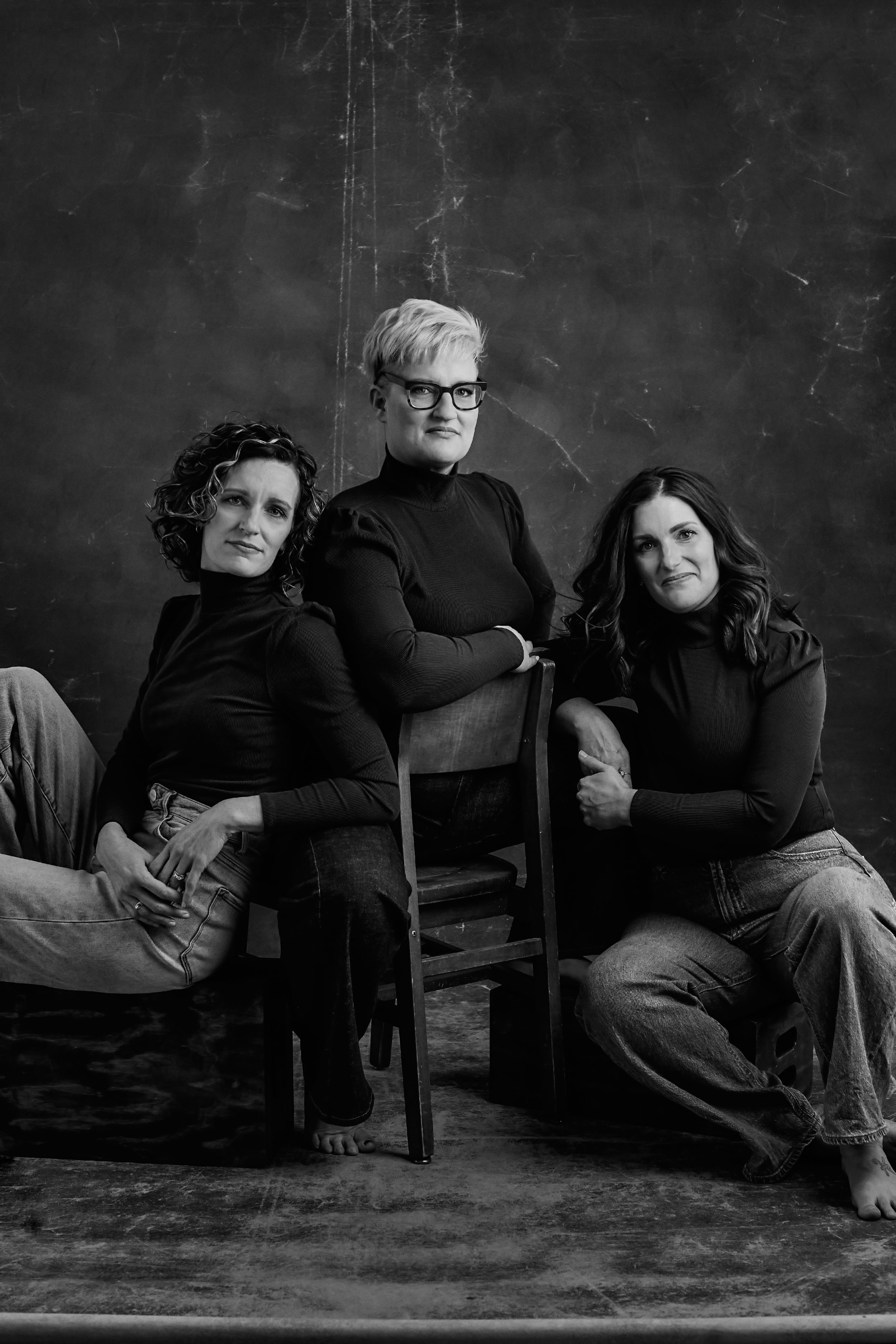 Artistic black and white series of people lounging and posing on chairs against dark backdrop.