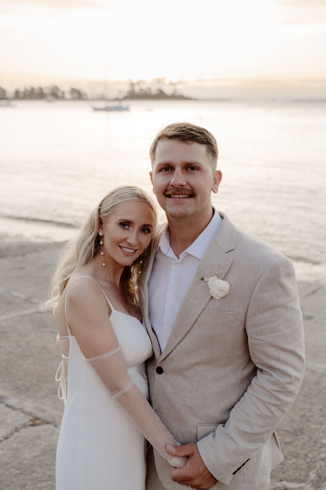 A photo of a happily married couple at their wedding smiling at the camera during golden hour