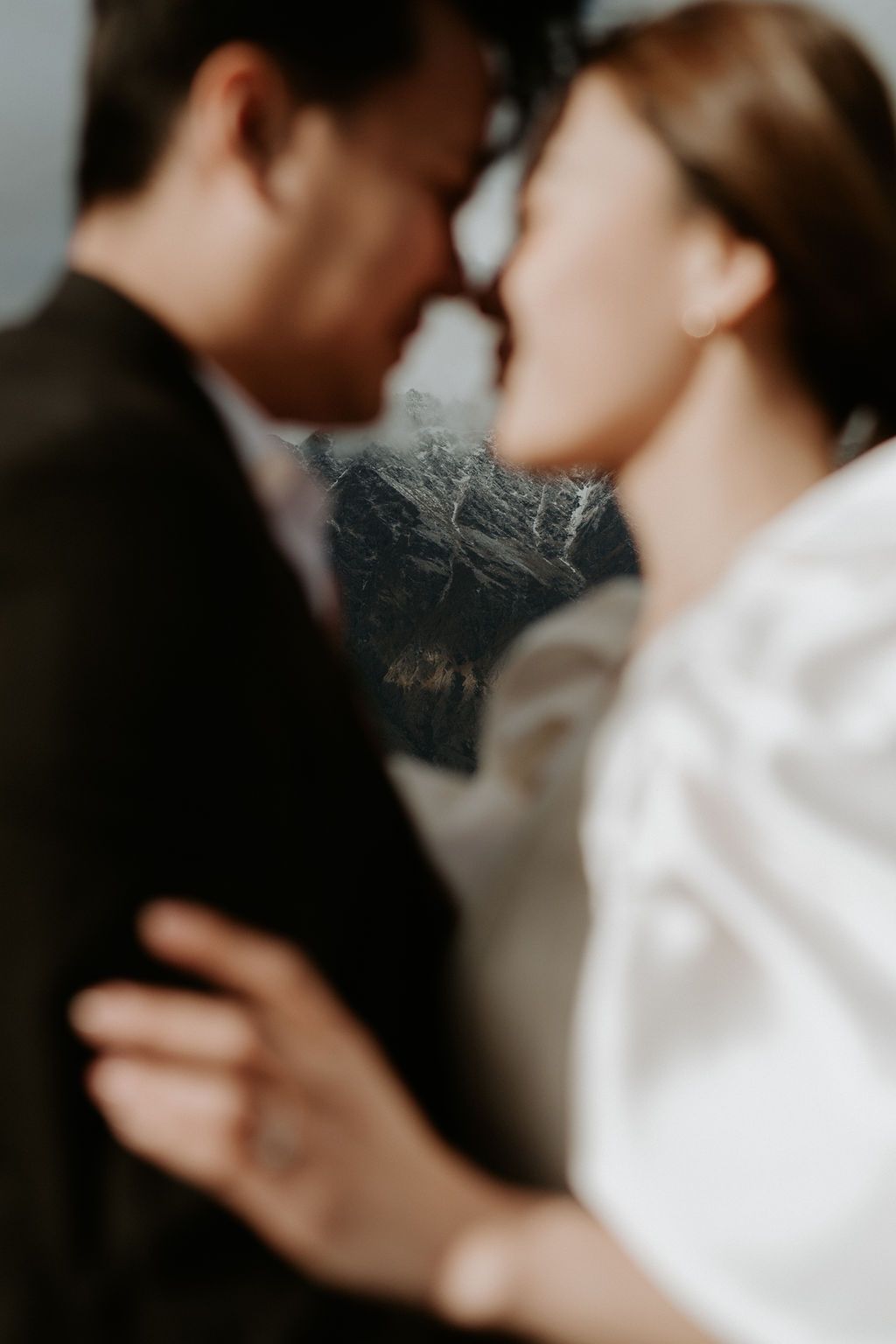 An out of focus artsy wedding image of a couple. You can see a Queenstown mountain in focus behind them