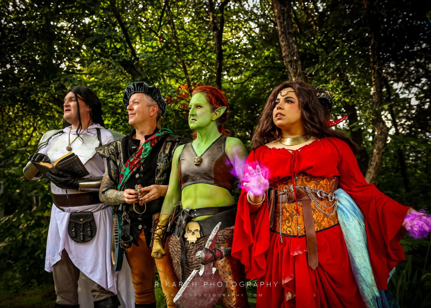 Fantasy cosplay group in medieval and magical costumes posing in woodland setting.