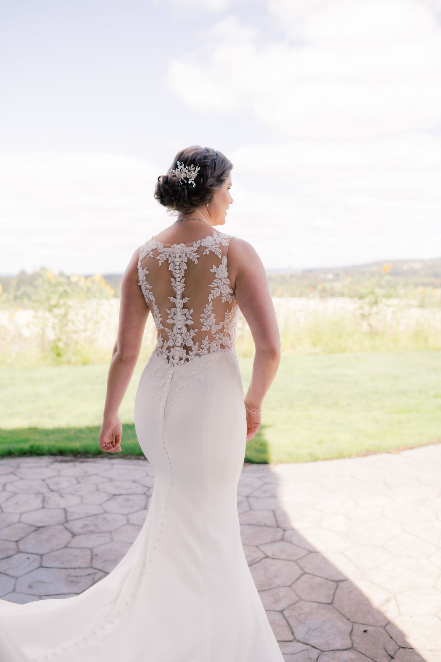 Back view of bride in fitted wedding dress with detailed lace illusion back panel.