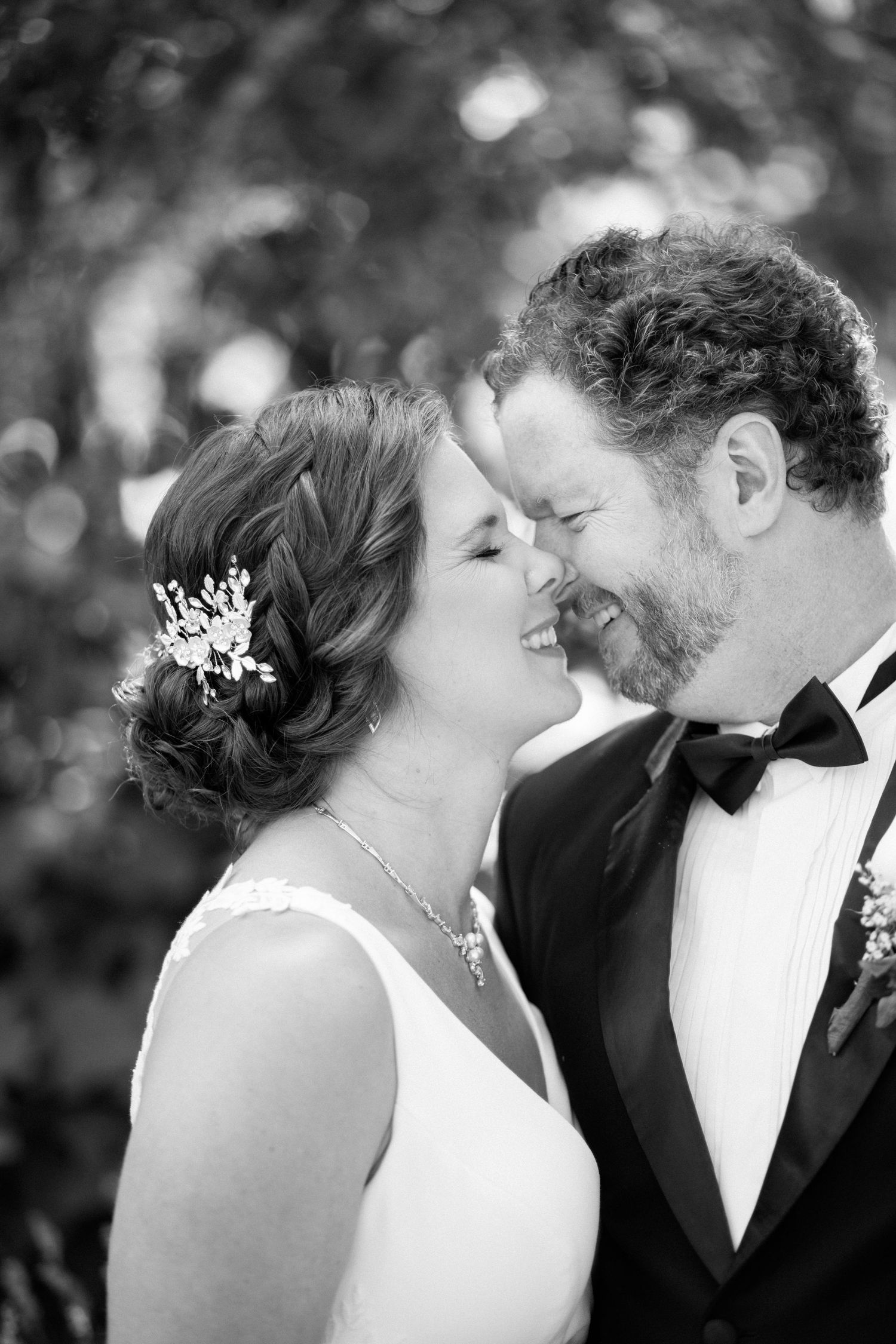 Intimate black and white portrait of newlyweds sharing a romantic moment outdoors.
