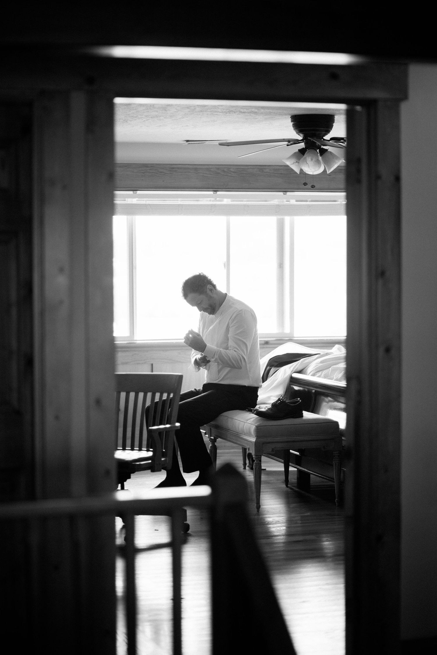 Black and white photo capturing quiet moment of preparation through doorway.