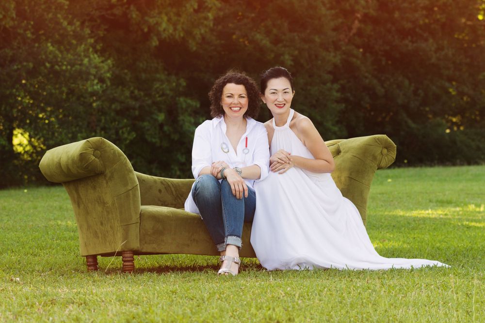 2 female friends sitting on a couch in a field