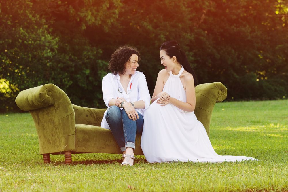 2 female friends sitting on a couch in a field
