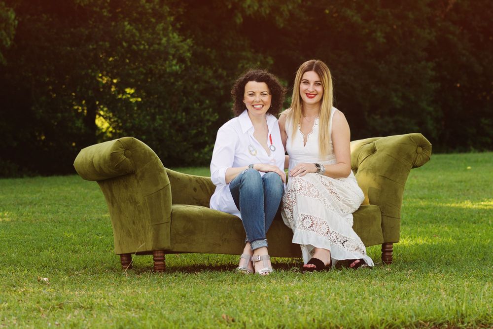 2 female friends sitting on a couch in a field