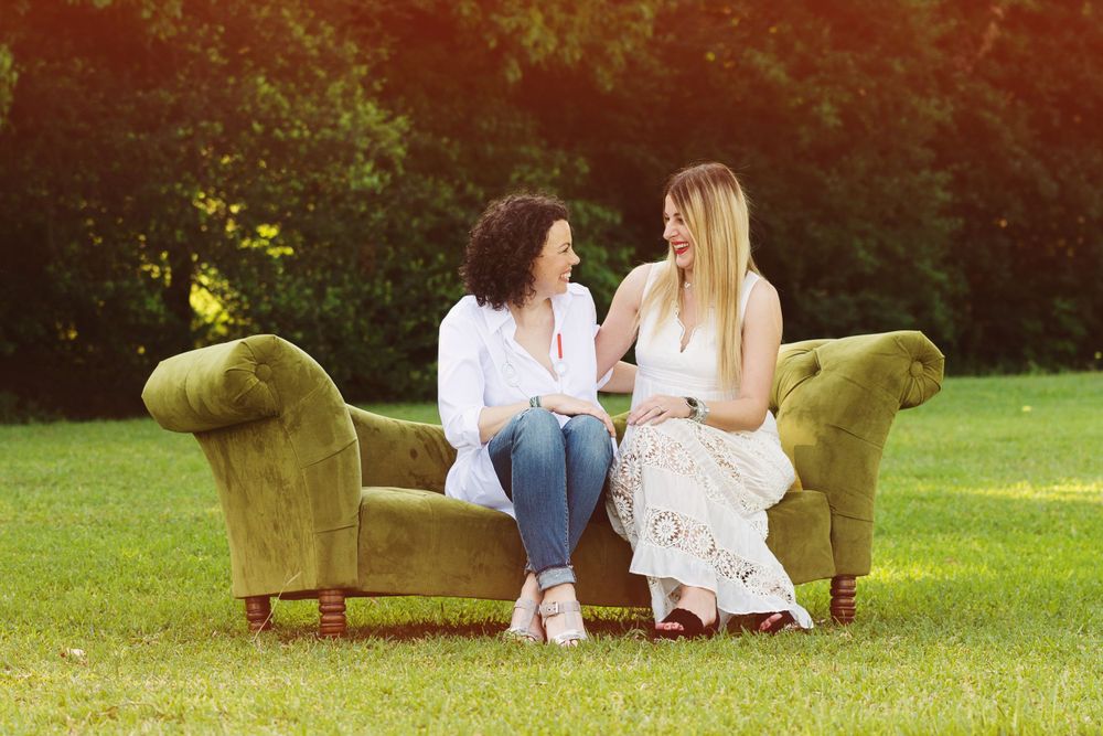 2 female friends sitting on a couch in a field