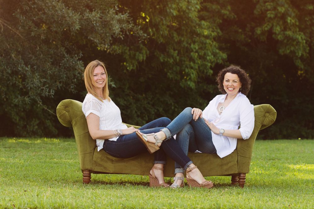 2 female friends sitting on a couch in a field