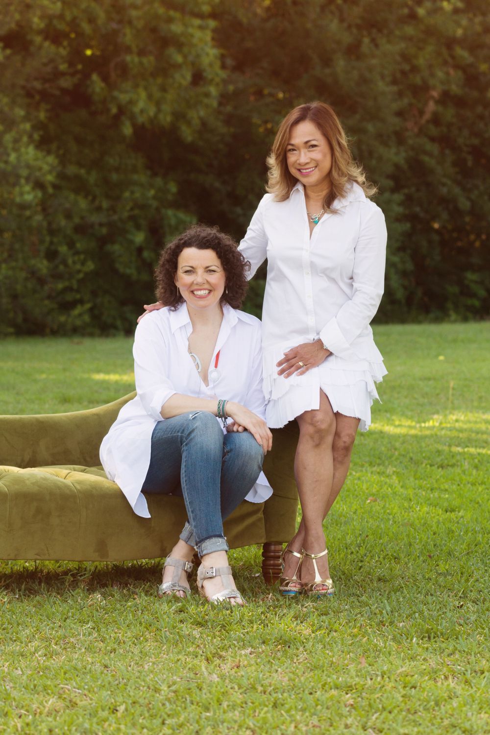 2 female friends sitting on a couch in a field