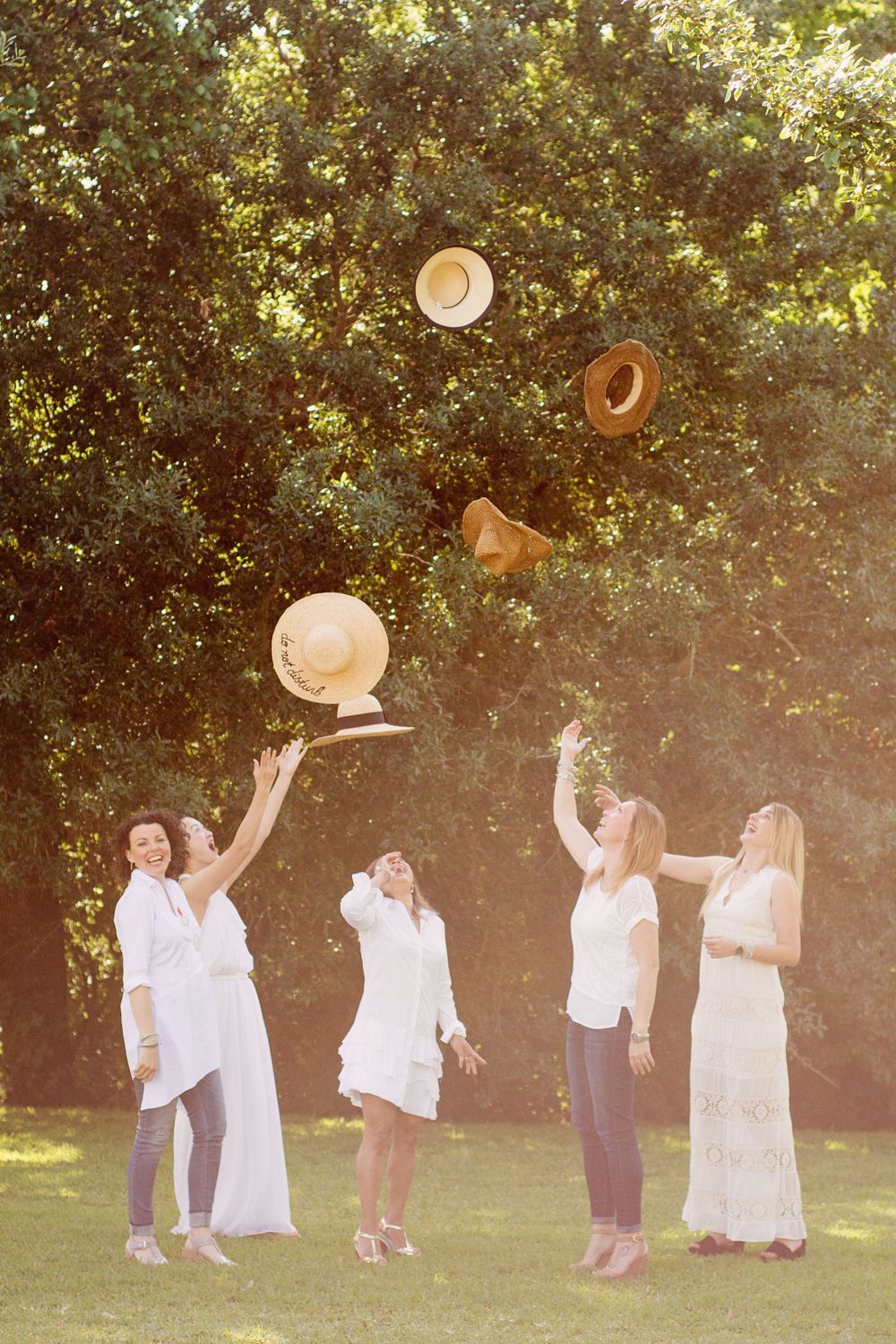 5 women tossing hats in a field