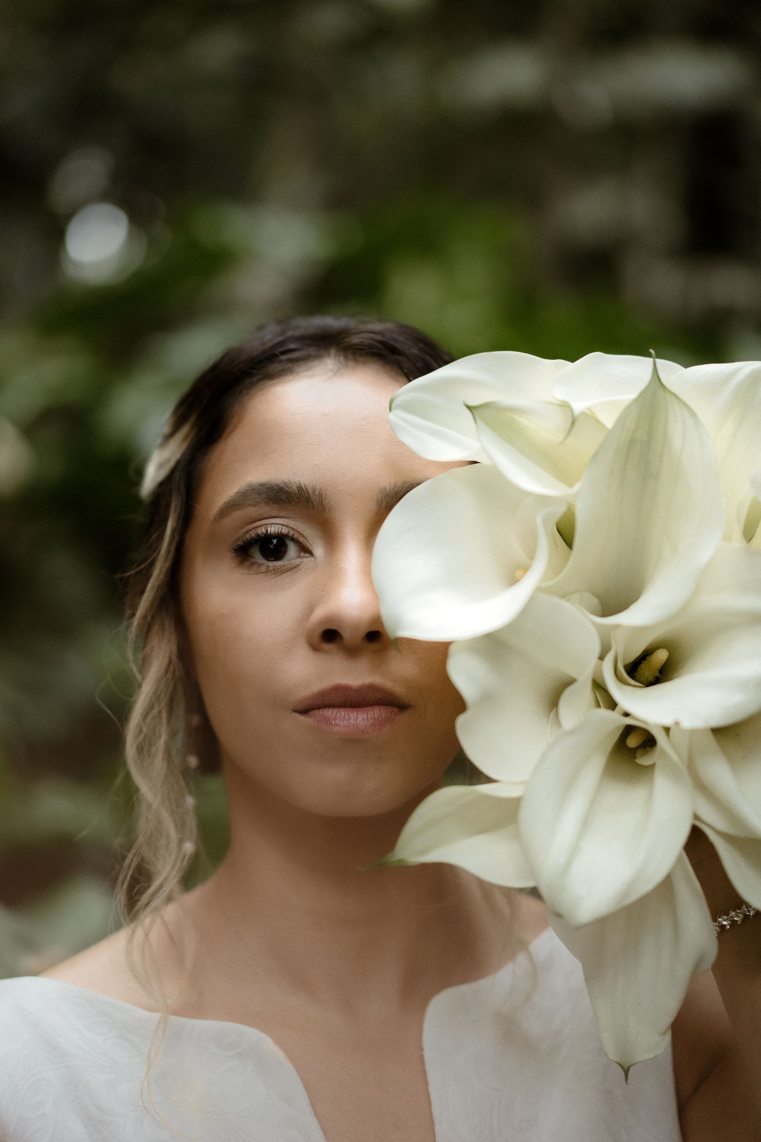Elegant white calla lily bouquet creates striking contrast in an artistic bridal portrait.