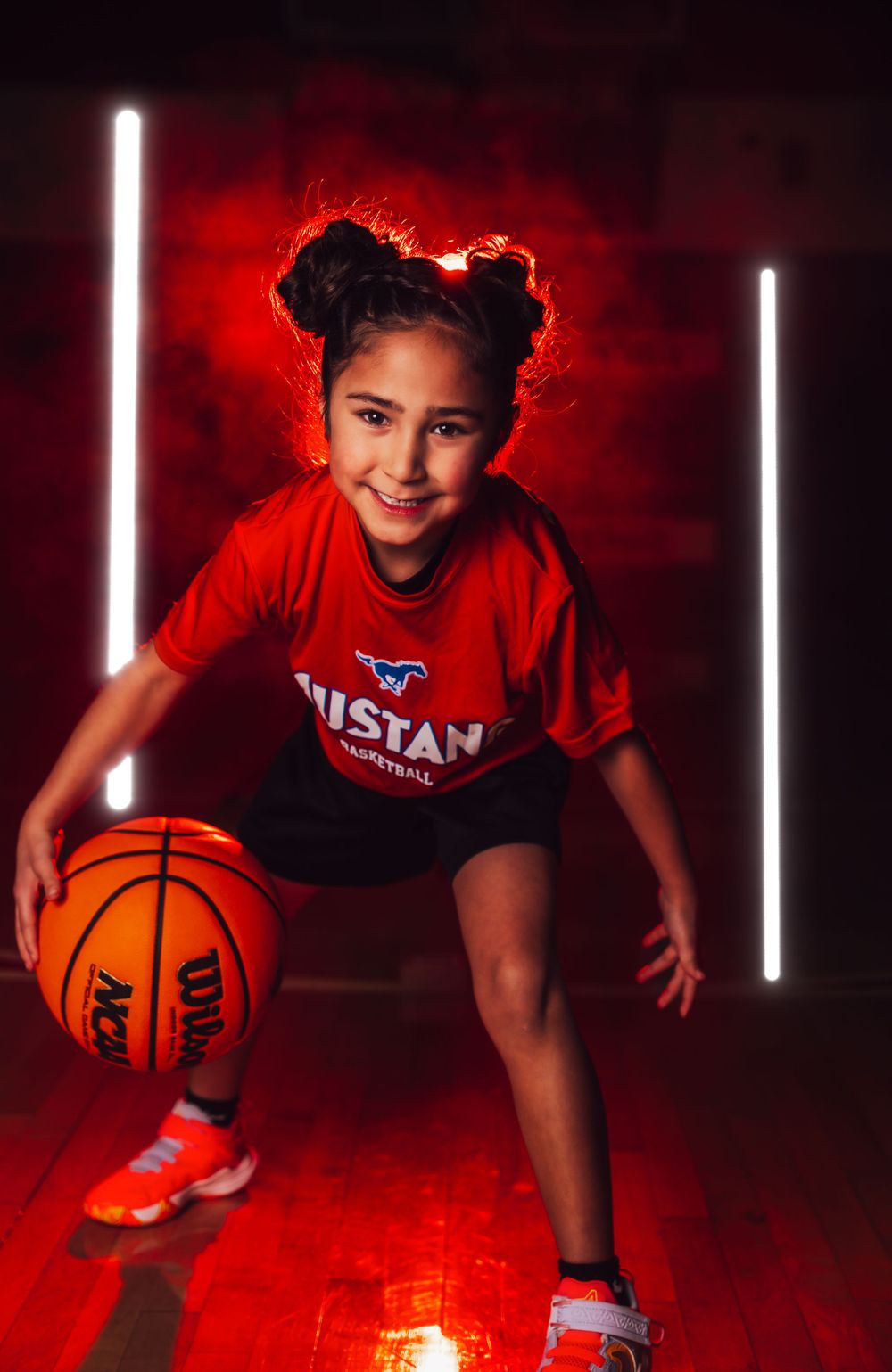 Dramatic red-lit basketball photo shoot on wooden court with vertical LED light bars.
