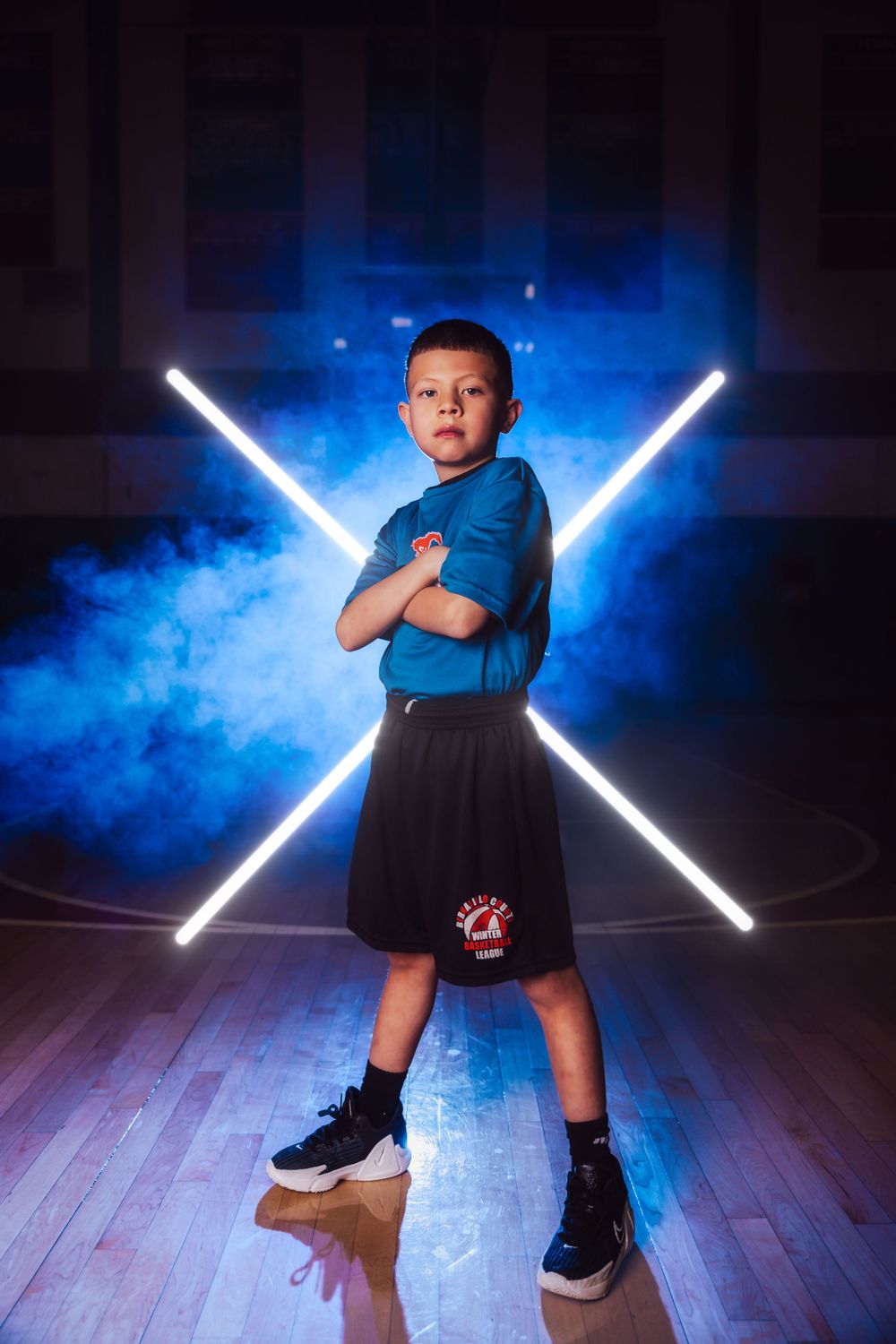 Youth basketball photo session with blue smoke effects and white LED lighting on hardwood floor.