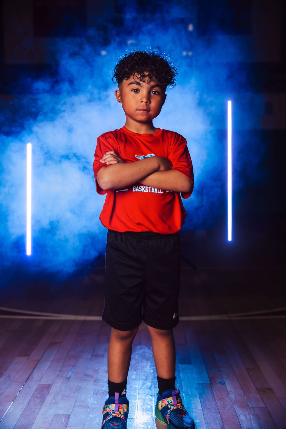 Athletic photo shoot featuring red uniform against blue smoke and vertical LED light bars.