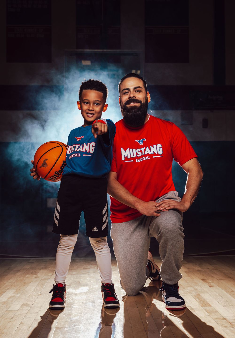 Basketball portrait with player and coach on wooden court with dramatic lighting.