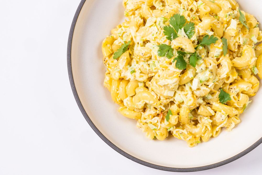 Creamy scrambled eggs garnished with fresh herbs served in white bowl on light background.