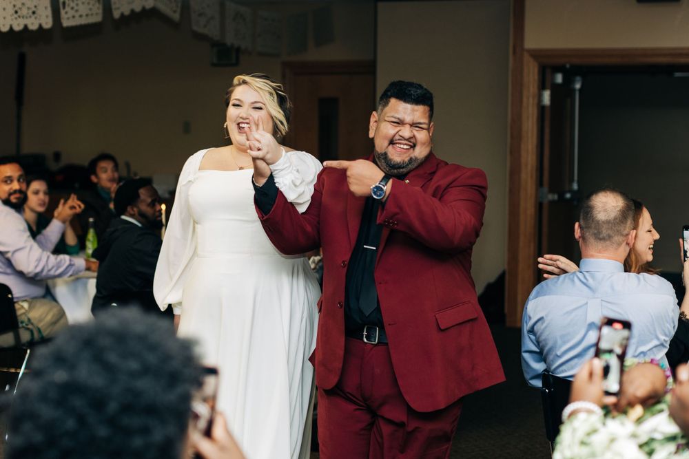 A couple dancing together at their wedding reception while guests watch and take photos.