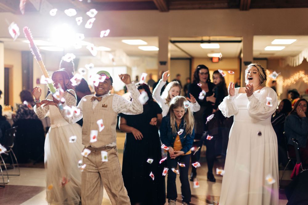 Wedding guests celebrate with confetti and sparklers during an indoor reception.