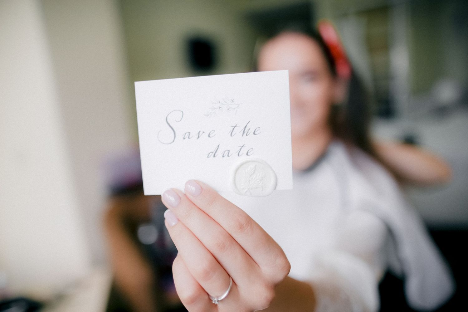 Hand holding elegant save the date card with calligraphy text.