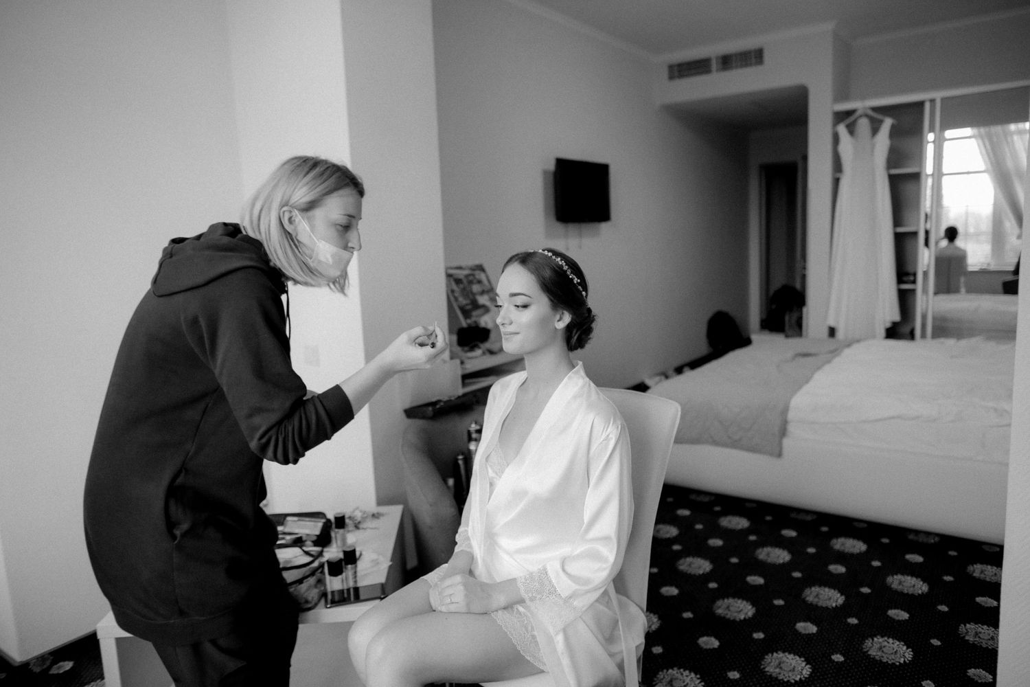 Makeup artist working on wedding day preparation in hotel room.