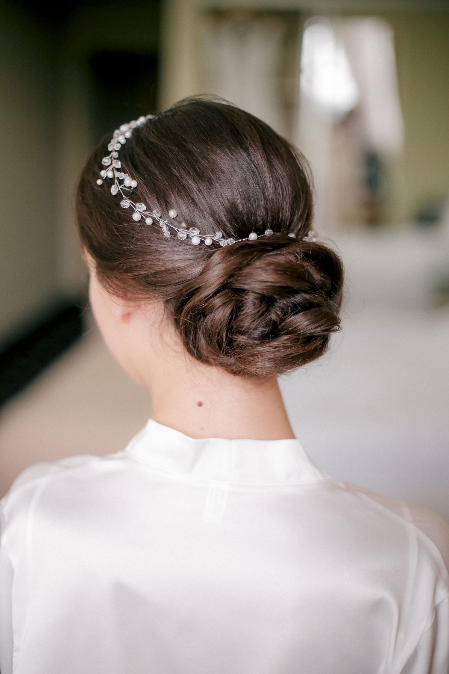 Back view of intricate bridal updo hairstyle with crystal hair accessory.