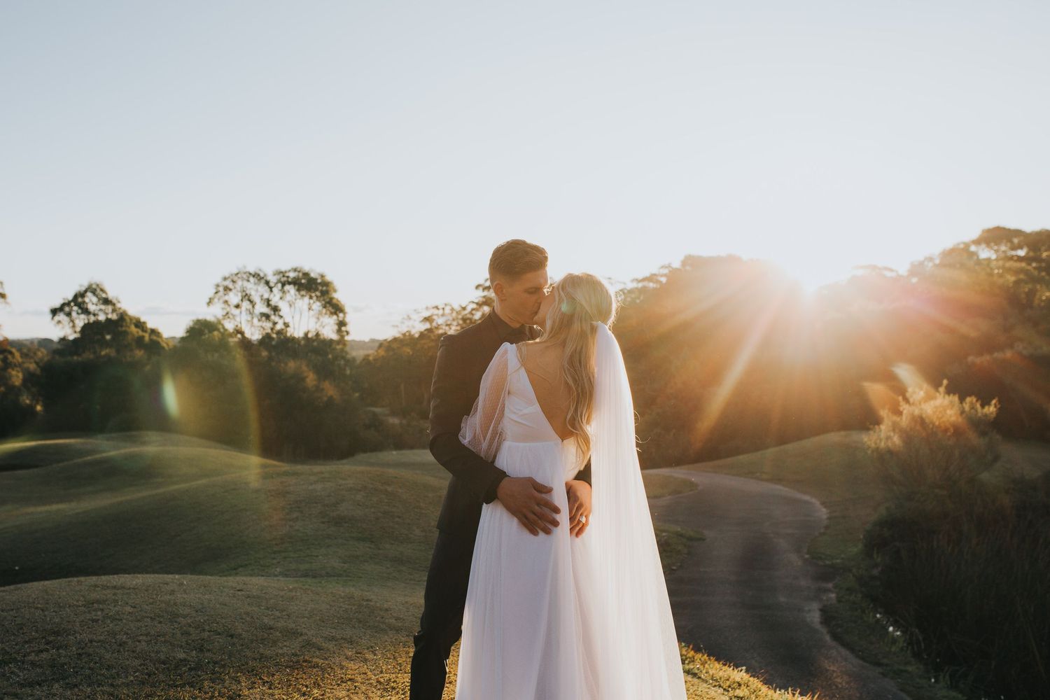 Wedding couple poses with their black and white dog while holding a white floral bouquet.