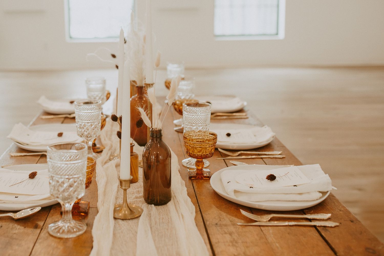 Elegant table settings with warm lighting and neutral decor in a rustic dining space.