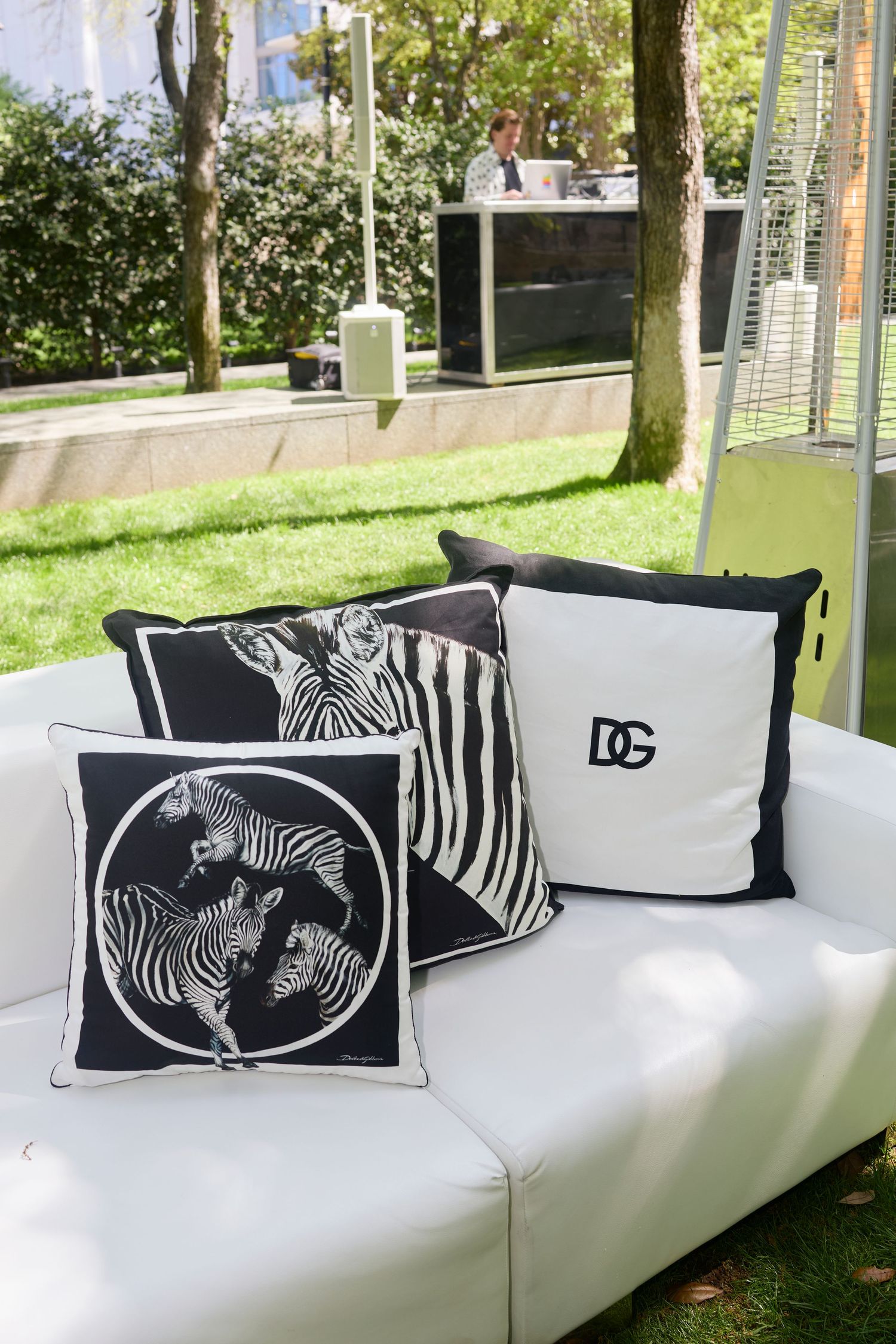 White outdoor lounge sofa with zebra print decorative pillows set in garden setting.