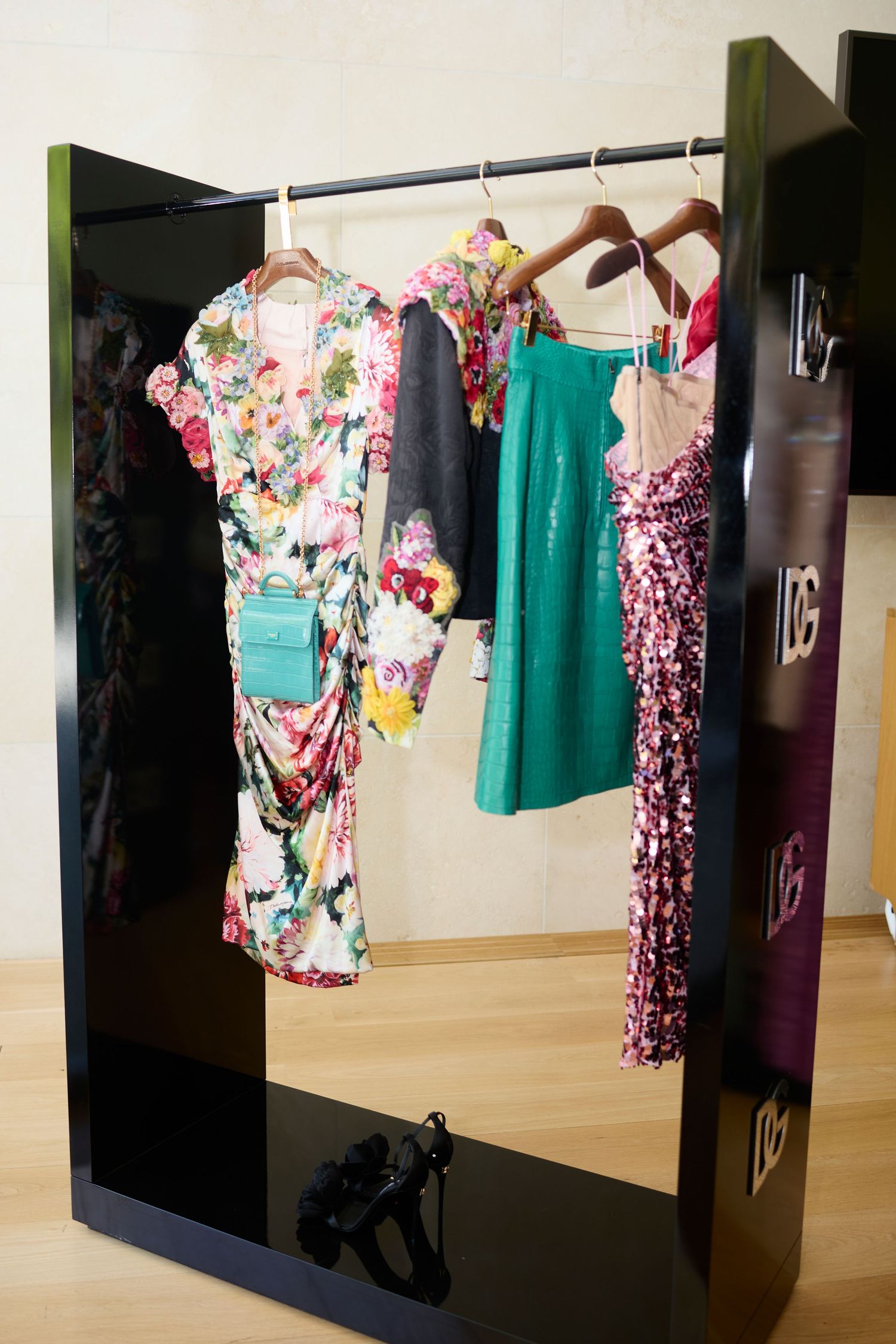 Colorful designer dresses and garments displayed on clothing rack at fashion retail event.