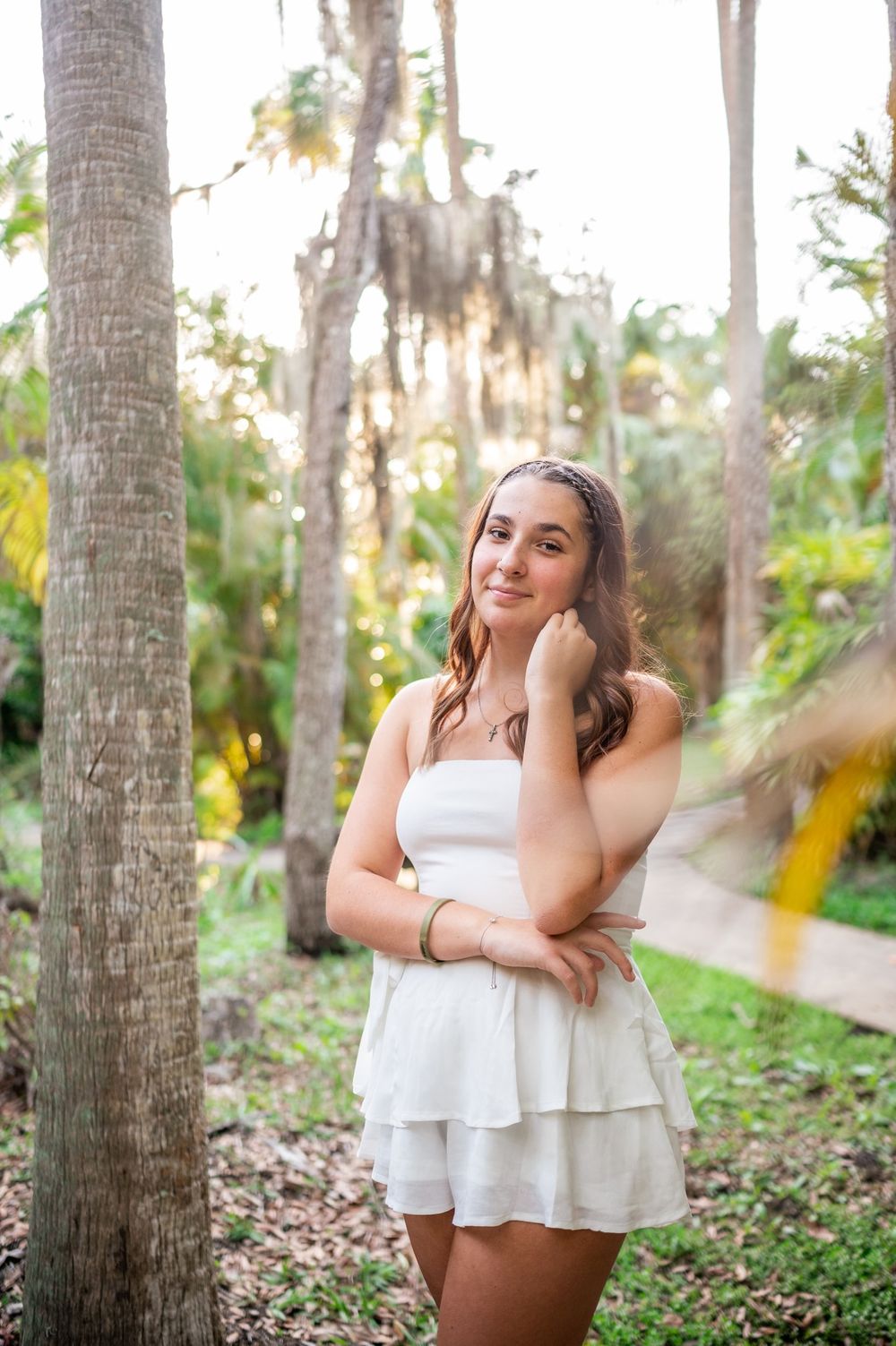 Senior girl graduation photoshoot session in white dress smiling standing in trees park sunset Melbourne Cocoa Vero Florida Brevard County