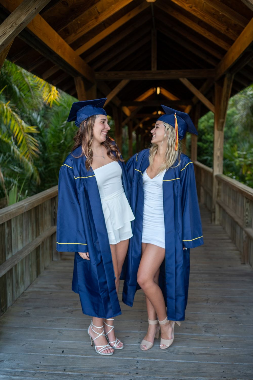 Two senior girls graduation photoshoot session in cap and gown smiling park friend sunset Melbourne Cocoa Vero Florida Brevard County