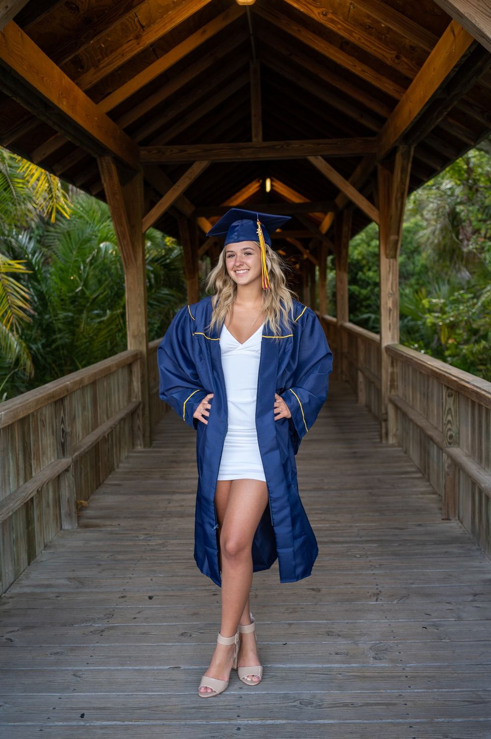 Senior girl graduation photoshoot session in cap and gown smiling standing in trees park sunset Melbourne Cocoa Vero Florida Brevard County