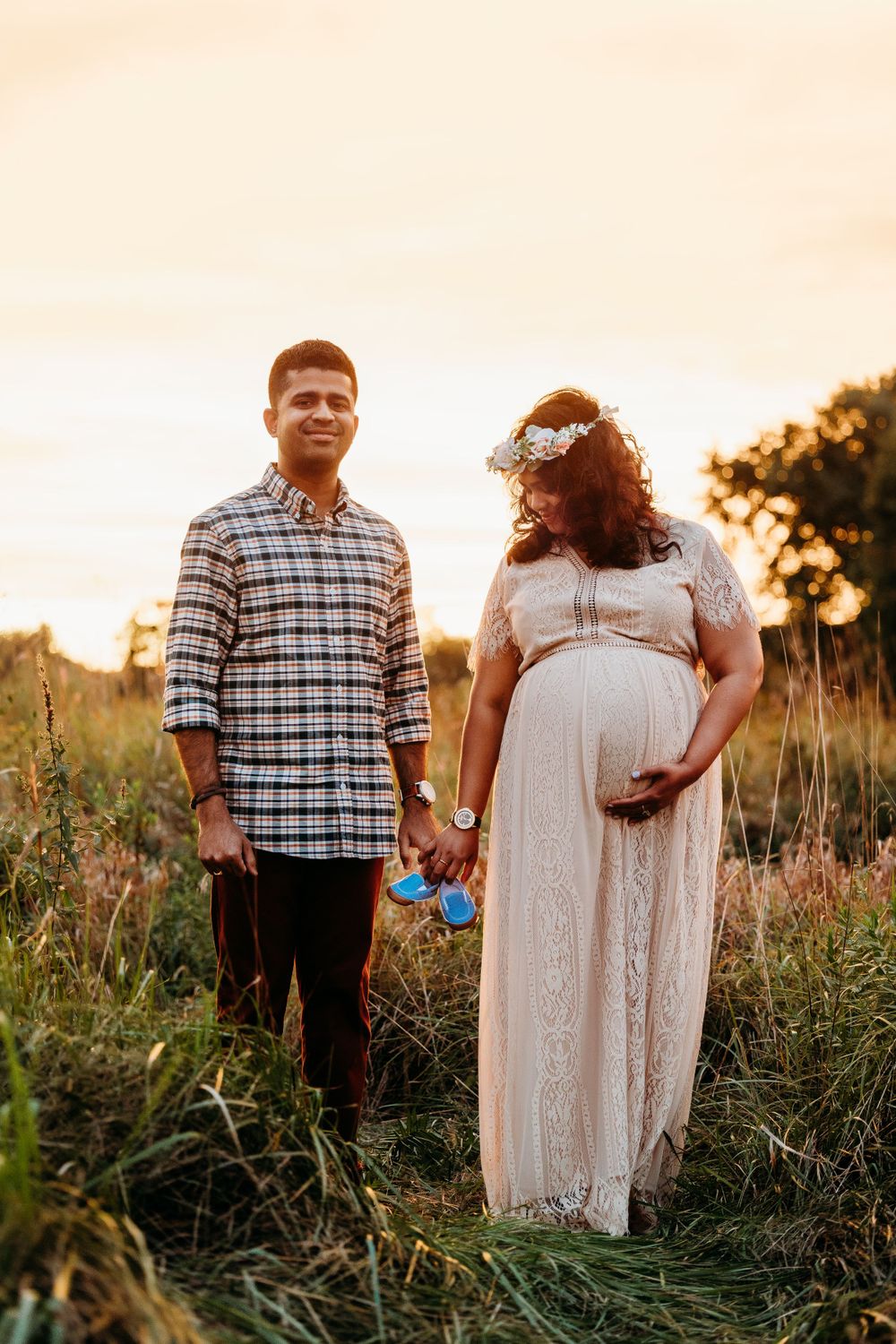 Couple poses together in a wildflower field at sunset wearing coordinated white outfits.
