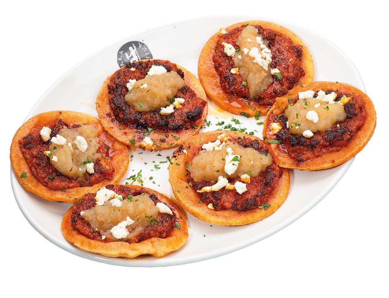 Tortos de maíz con salsa de tomate, queso feta derretido y hierbas servidas en un plato ovalado blanco. Tierra Astur
