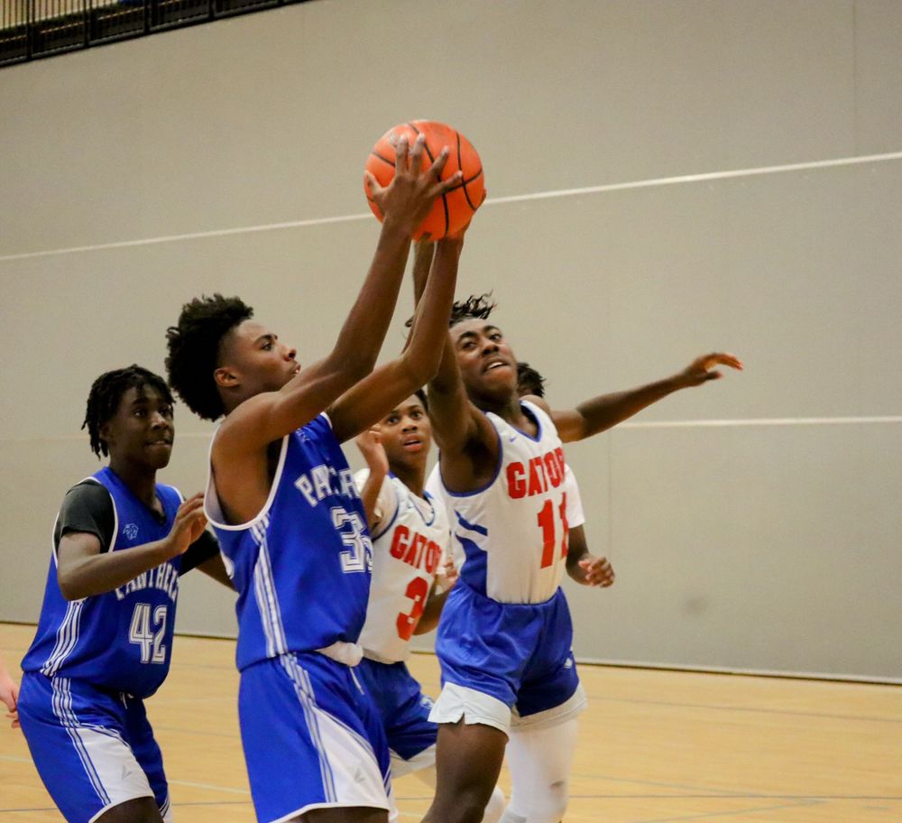 Basketball players in blue and white jerseys compete for the ball during an intense game sequence.