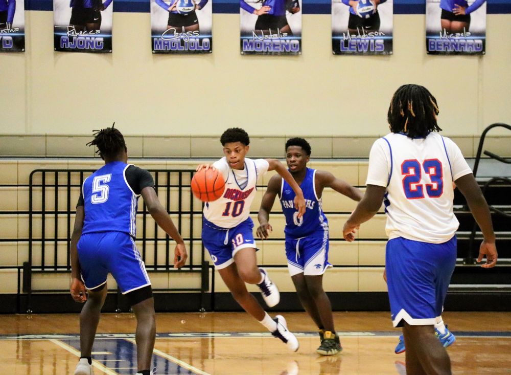 Basketball players leap and compete for possession during a competitive indoor game.
