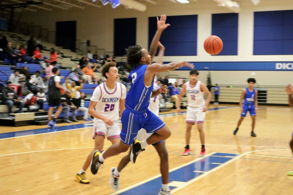 Action shot of basketball players in blue and white jerseys competing for possession during a game.