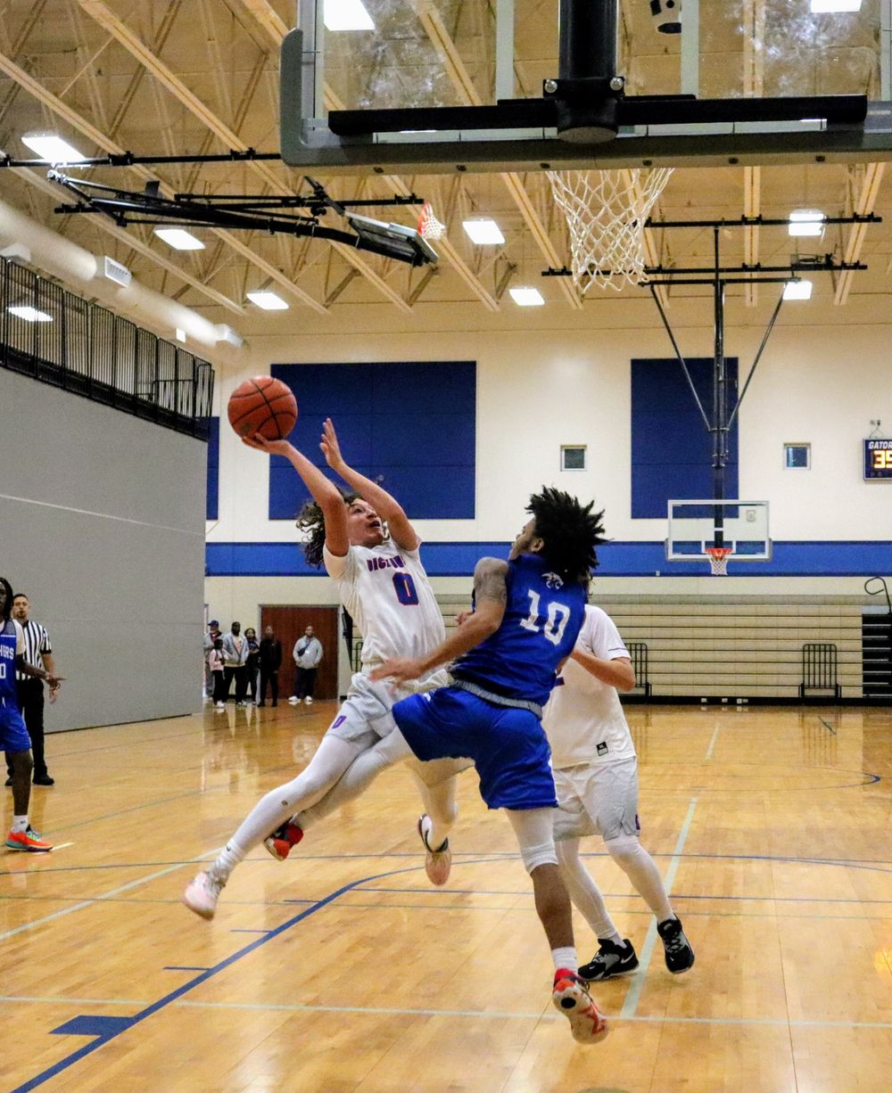 Basketball players leap and stretch for the ball during an intense moment of gameplay.