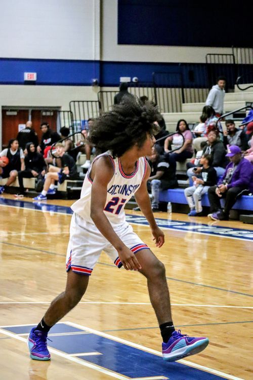 Basketball players in motion during an intense defensive play on the court.