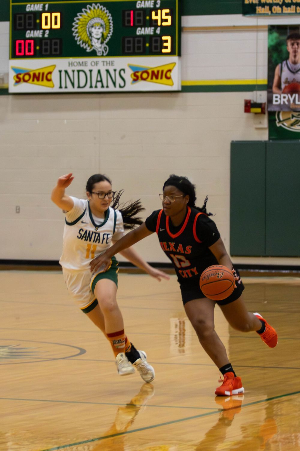 Players chase after a loose basketball during a fast-paced game on the court.