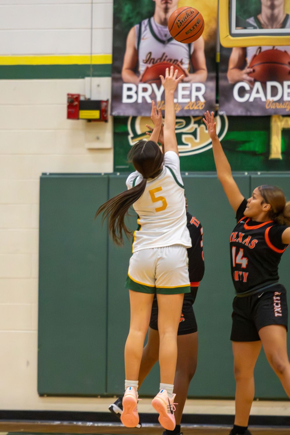Players from opposing teams compete for possession of the basketball during a high school game.