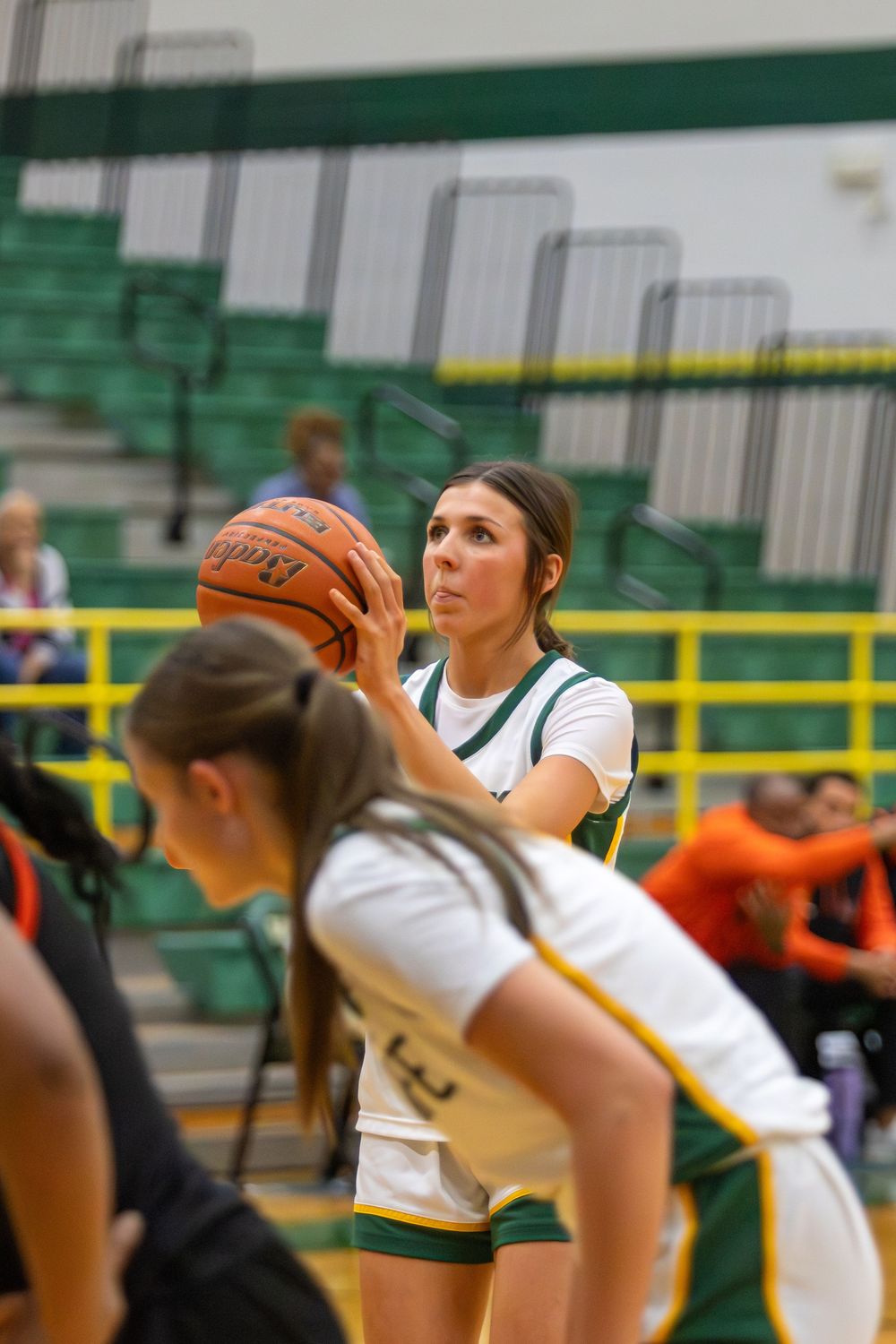 Players reach high to grab a basketball during a competitive game in a school gymnasium.