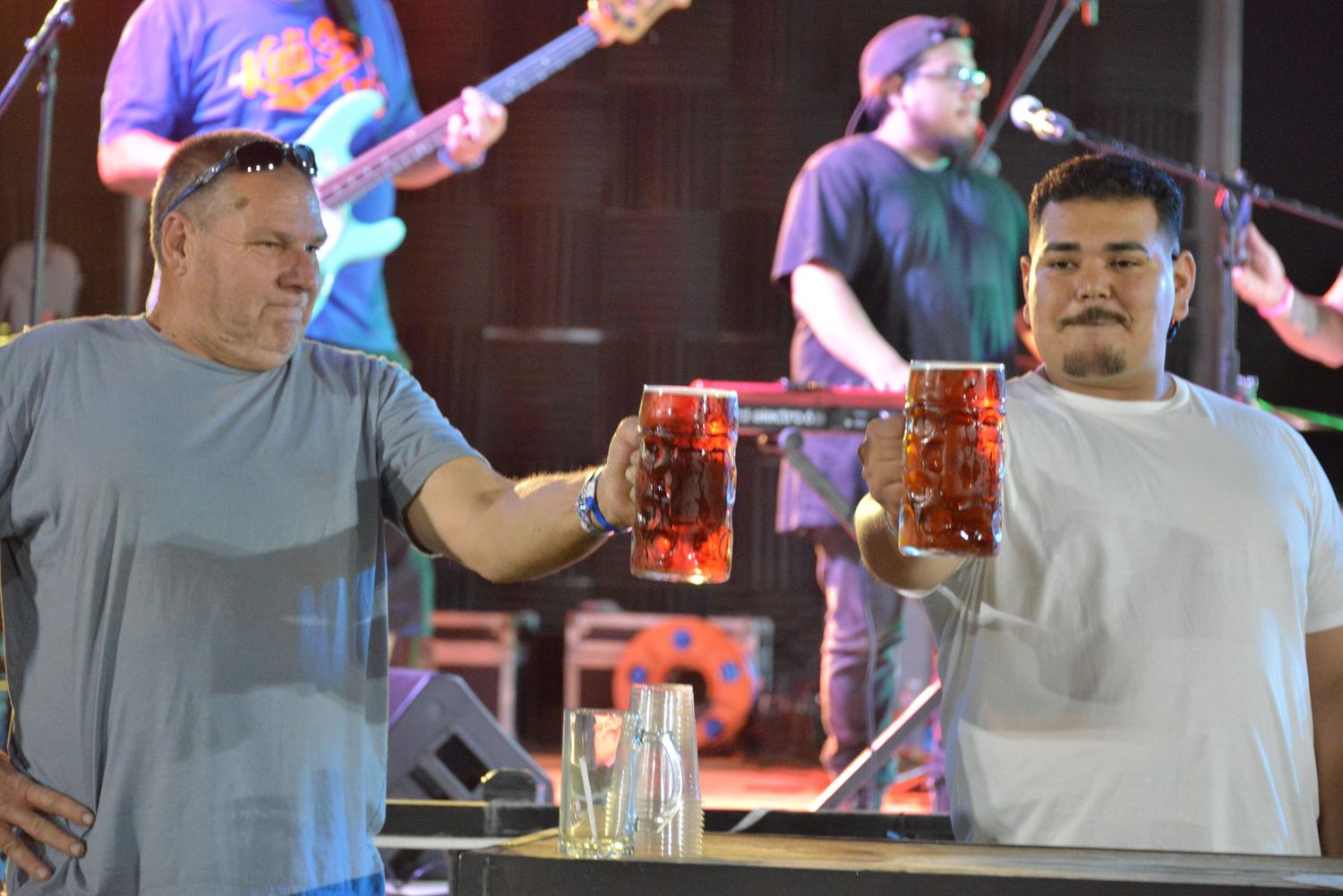 People cheering and toasting with beer glasses at what appears to be a festive gathering or celebration.