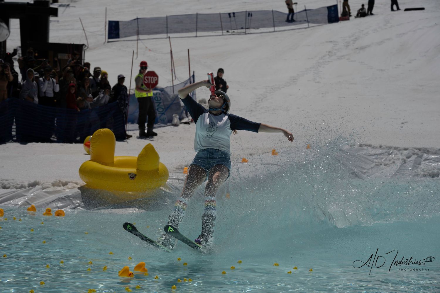 Person skimming across pool surface with yellow rubber duck during winter sports competition.