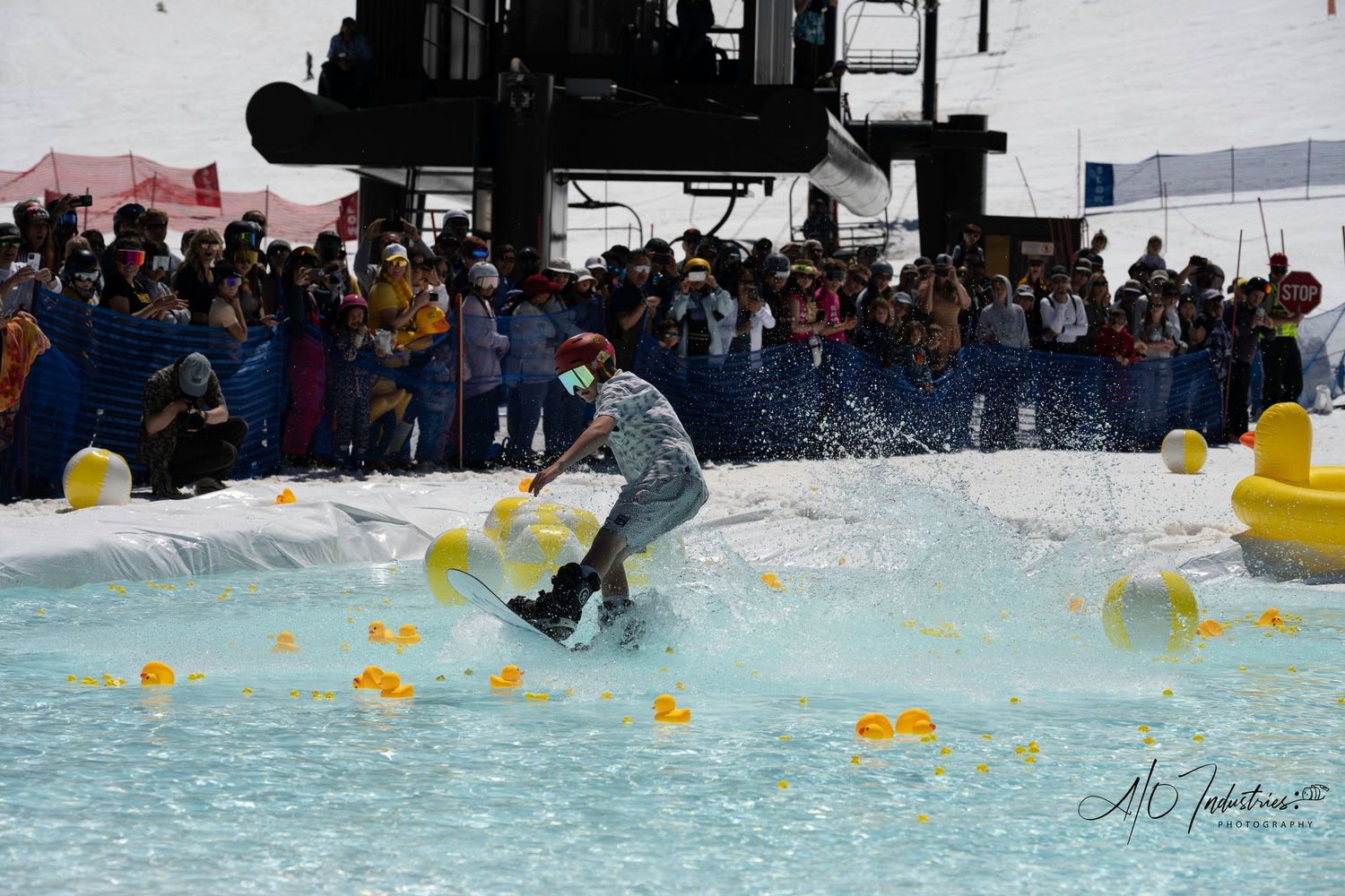 Skilled skier glides across pool of water with rubber ducks during spring skiing event.