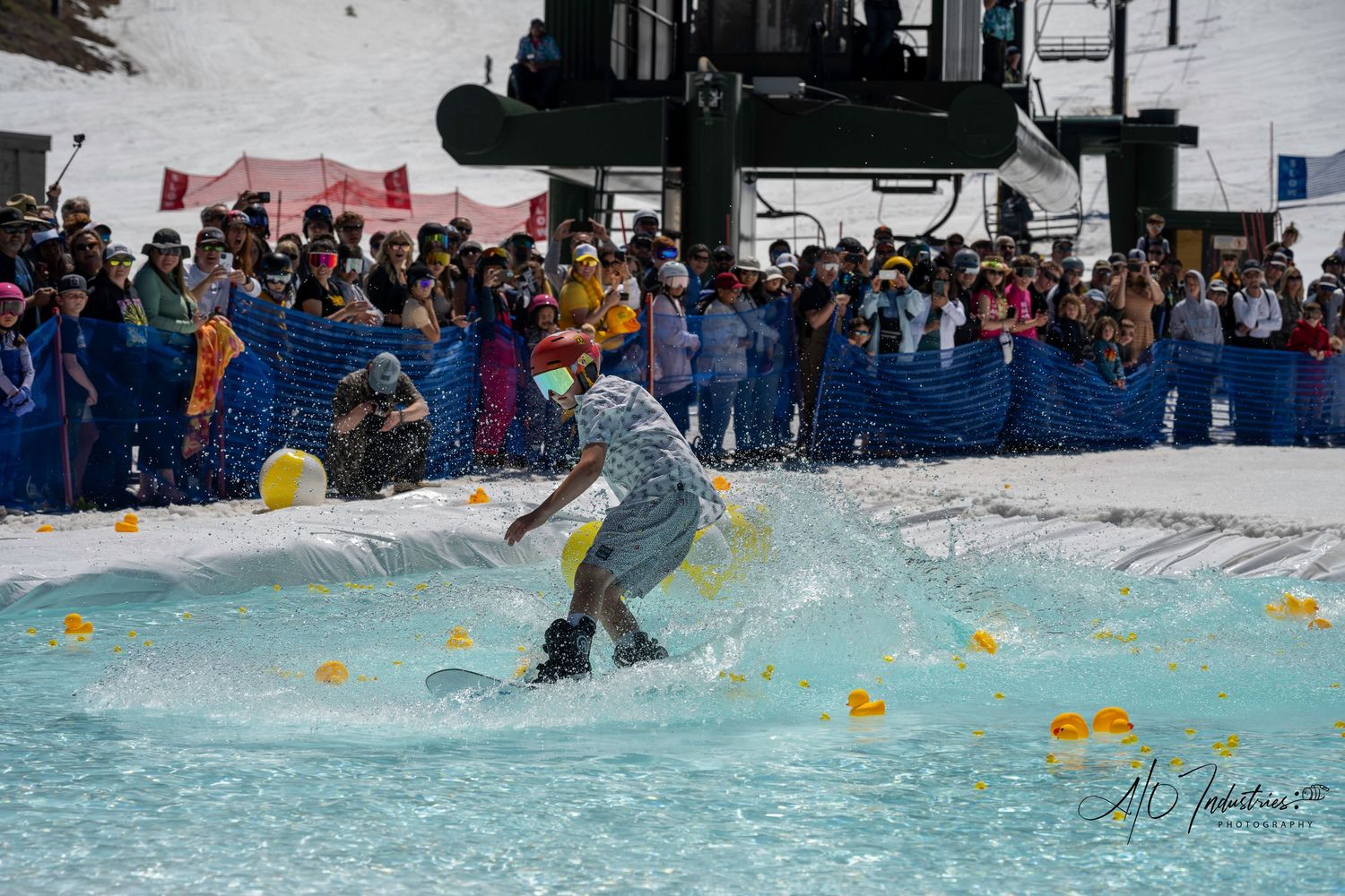Skier launches off snow into water pool during spring pond skimming competition.