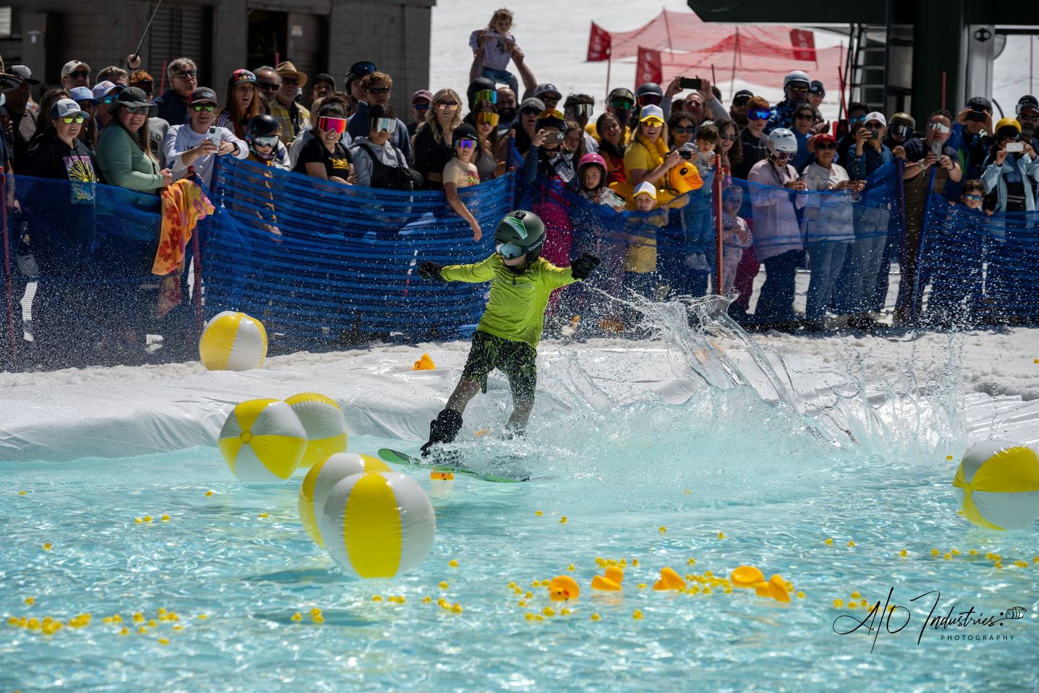 Skier attempts to cross pool filled with yellow balloons as crowd watches from behind barriers.